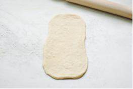 毛毛虫面包,然后翻面，拽开椭圆形面饼的两端，擀成长方形；