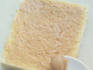 芝士火腿西多士,均匀的将花生酱涂抹在已切边的切片面包上