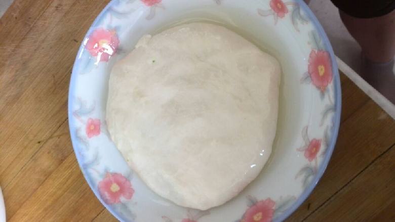 猪肉茴香馅饼,等面醒好后，手沾油揪出一个小面团放入涂好油的盘子当中，摊薄把馅包进去。