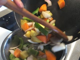 法式迷迭香烤小羔羊排,放入切好的胡萝卜、土豆和圆椒继续翻炒，并撒少许盐和黑胡椒后关火