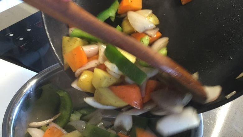 法式迷迭香烤小羔羊排,放入切好的胡萝卜、土豆和圆椒继续翻炒，并撒少许盐和黑胡椒后关火
