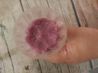 双色山药糕,取一个紫色圆球放进月饼模具中，用手稍微压扁。