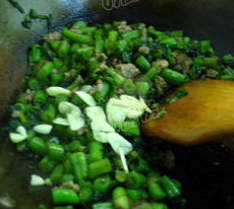 橄榄菜肉沫四季豆,加入炒好的肉馅，蒜片，翻炒出锅