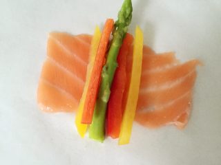 彩蔬鱼片卷,将三文鱼片展开，平铺，放上芦笋和彩蔬细条，然后顺势卷起来就好啦。