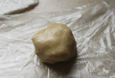 广式椰蓉月饼,用刮刀拌至絮状后，揉成面团，揉好的面团包上保鲜膜静置1个小时