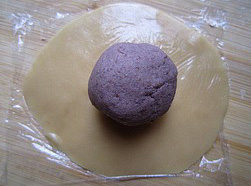 广式豆沙月饼,小球放在保鲜膜上，按成圆片（大小以包住豆沙馅即可。），放上豆沙馅
