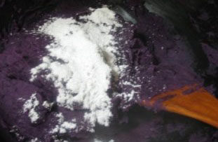 广式紫薯坚果月饼,紫薯一直翻炒至水分消失，然后加入适量的小麦淀粉继续翻炒均匀，盛出放凉备用。