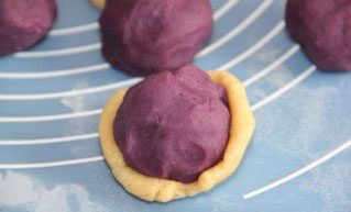 广式紫薯坚果月饼,将饼皮按扁，包入紫薯馅