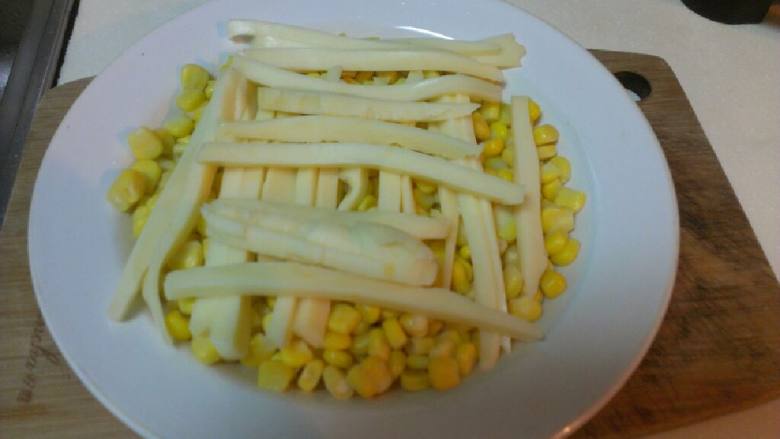 三分钟微波搞定的--奶酪玉米,玉米铺在盘子里，上面放上奶酪条。
