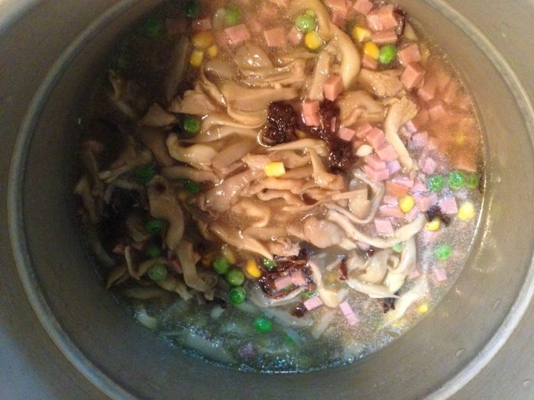 蘑菇什锦烩饭,将松仁小肚丁、玉米粒、青豆粒、炒好的蘑菇连汤一并放入高压锅