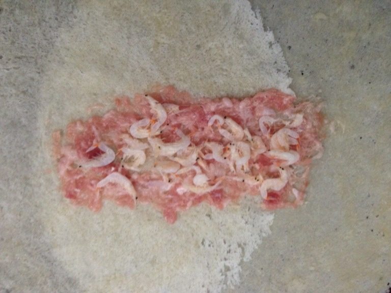 潮式春卷,把备用的虾皮子摆至抹平的肉末上。