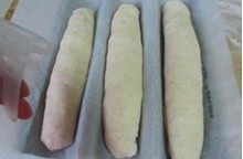 越嚼越香的“核仁葡萄干全麦面包棍”,将整理成长棍的面包放在饧发的模具上，表面喷些水