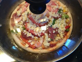 平底锅版--蔬菜披萨,平底锅烧热，放入黄油，然后将披萨饼放入小火煎到芝士融化冒泡，大概6~7分钟后就可以吃了。