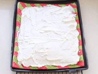 圣诞树蛋糕,再将蛋糕卷模具覆盖在蛋糕胚上翻过来，表面涂抹打发好的奶油，靠近身体的这一端可以涂抹厚一些，上面边缘薄一些。