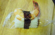 寿司拼盘,取一块米饭，取掉保鲜膜，米饭上面摆上一只虾或三文鱼或蟹腿肉，取海苔条，绕在米饭和海鲜上，固定住表面的海鲜