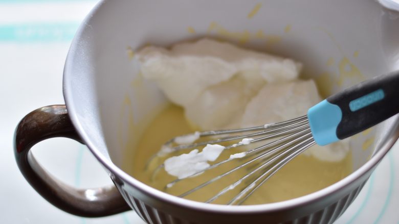 奶酪芝麻戚风,取一部分蛋白霜加入蛋黄糊，翻拌均匀，再加入一部分蛋白霜继续用刮刀翻拌