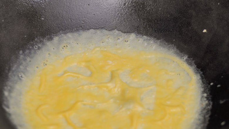 蛋包黑米饭, 开小火加热锅，用汤勺舀35ml左右的鸡蛋液倒入热锅中，转动锅使蛋液均匀铺在锅底，揭下做好的蛋饼装盘。
