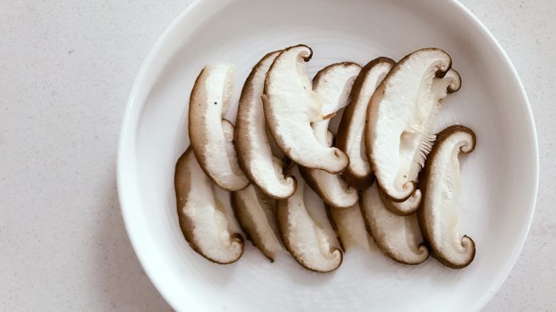 宝宝辅食：香菇蒸鳕鱼,在盘子底部垫上一半左右的香菇片。