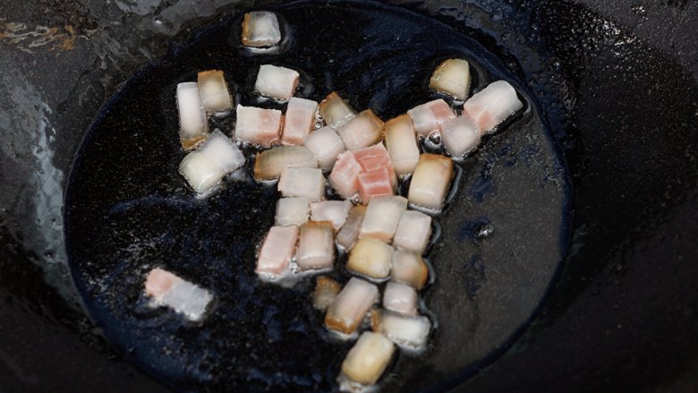 蚕豆火腿焖饭,锅中油热后放肥火腿爆香。