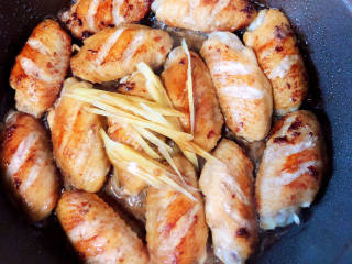 雪碧鸡翅,煎好鸡翅，放入姜丝，倒入腌鸡翅的料。