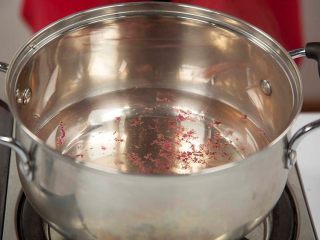 花茶玄饼,将花茶水倒入锅中，煮沸。取几朵玫瑰花干拧碎，将拧碎的玫瑰花瓣撒入锅中煮沸