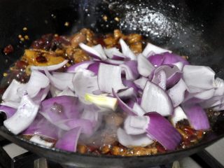 香辣干锅兔, 水份收得差不多的时候，倒入洋葱，继续翻炒。