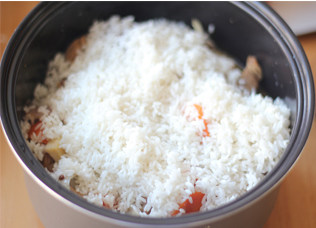 家常手抓饭,中小火炖至汤汁剩一半，转入电饭煲，在上面铺上泡好的大米，用正常煮饭程序，蒸熟即可，吃的时候搅拌均匀