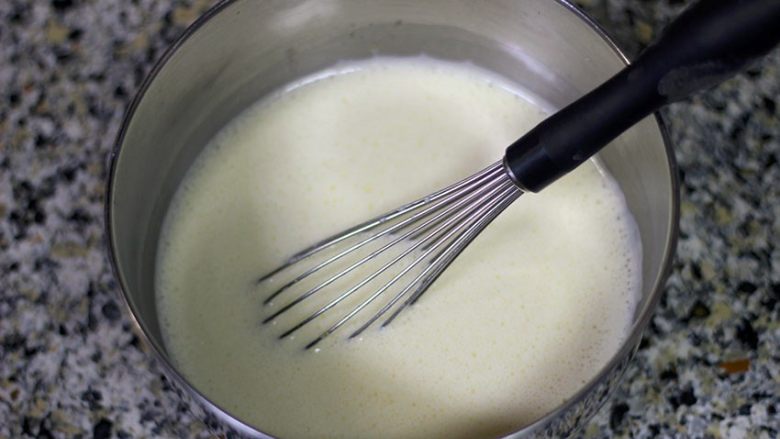 舌尖上的芒果浮云卷,将煮沸的牛奶淡奶油倒入蛋黄中，搅拌均匀