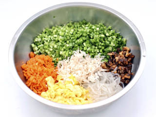 什锦素包,把切碎的韭菜和胡萝卜放入盆中，放入虾皮和切碎的香菇和粉条，炒熟的鸡蛋。