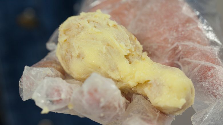 愚人节鸡腿蛋糕,取出固定成型的鸡腿，将裸露在外面的“鸡腿”部分均匀地抹上一层奶油霜。