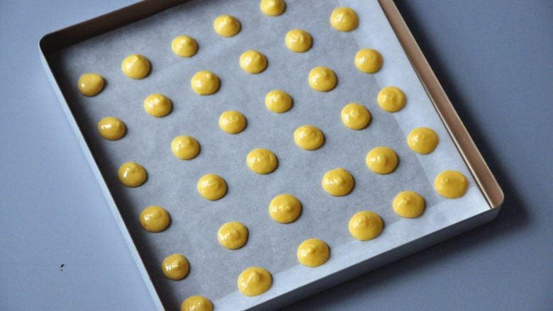 蛋黄饼干,为了方便脱模，在金盘中垫油纸，在上面挤出圆形面糊，注意要留一定间距。