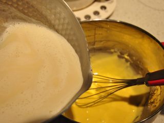 日式豆乳盒子蛋糕,煮开的豆浆分次加入到蛋黄糊中，一边加一边不停的搅拌。
