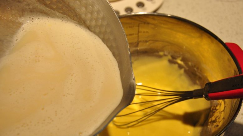 日式豆乳盒子蛋糕,煮开的豆浆分次加入到蛋黄糊中，一边加一边不停的搅拌。