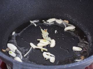 芹菜木耳炒肉丝,就锅中底油放入蒜片和姜丝，小火炒出香味。