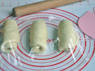 黄油椰蓉吐司条,将面团擀开卷成圆筒状，3个都做同样处理，盖上保鲜膜静置15分钟左右。