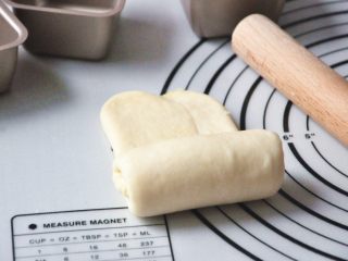 淡奶油椰蓉面包卷,面团包好椰蓉馅，左右折叠后擀成牛舌状，如果想层次好一次，可以擀薄一点，从下往上慢慢卷起。