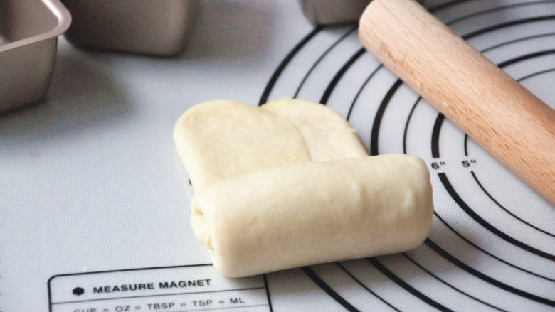 淡奶油椰蓉面包卷,面团包好椰蓉馅，左右折叠后擀成牛舌状，如果想层次好一次，可以擀薄一点，从下往上慢慢卷起。