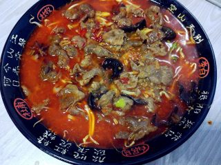 麻辣水煮牛肉,连汤带肉片一起倒入之前铺好豆芽和小油菜的大碗中。