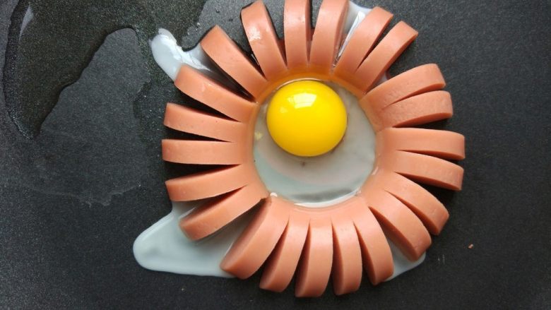 早餐——花朵香肠煎蛋,红色香肠也是如此处理。如果锅底不热，打入鹌鹑蛋后，底部不能马上凝固，会流到香肠外面去的