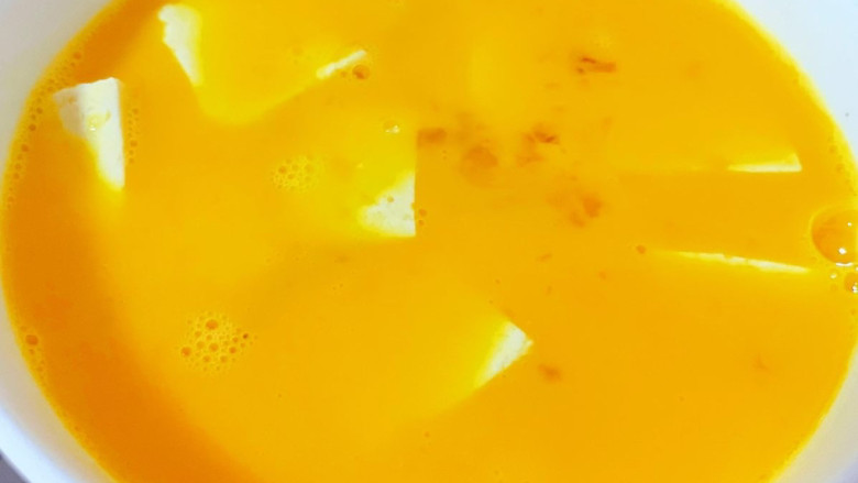 鸡蛋炖豆腐,鸡蛋打散搅拌成蛋液倒入豆腐中拌匀