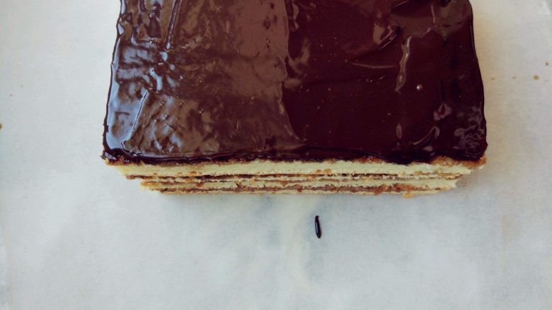 欧培拉歌剧院蛋糕,表面淋镜面巧克力淋浆，用抹刀抹两三次。我的巧克力比较少，如果量多，可以重复淋一次