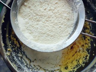 鸡尾酒磅蛋糕,加入过筛的低筋粉和泡打粉混合物，拌匀到没有干粉。有橙皮碎也可以加入一勺提香。