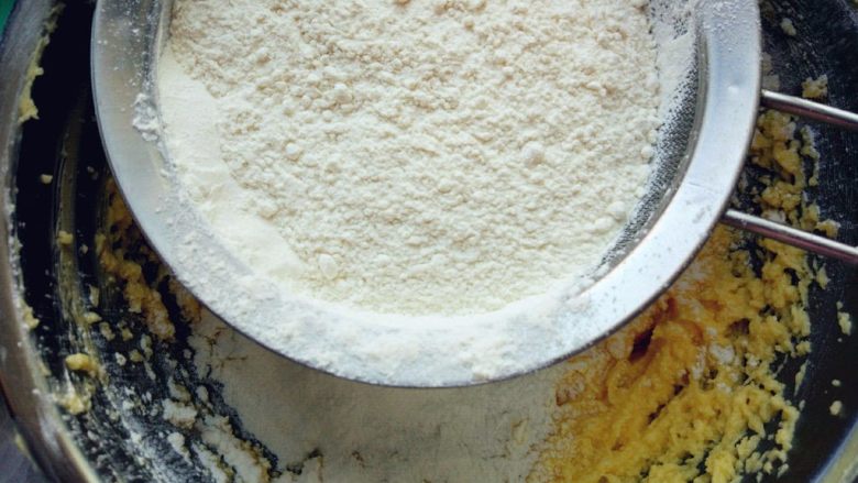 鸡尾酒磅蛋糕,加入过筛的低筋粉和泡打粉混合物，拌匀到没有干粉。有橙皮碎也可以加入一勺提香。