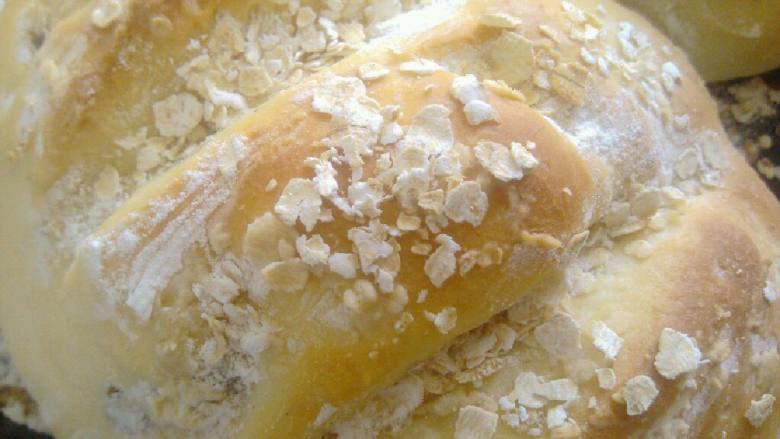 阳光健康面包,在烤盘上整理出一个橄榄形状，撒上麦片，拍一点干面粉在表面，用刀拉几条横纹，静至40分钟二次发酵