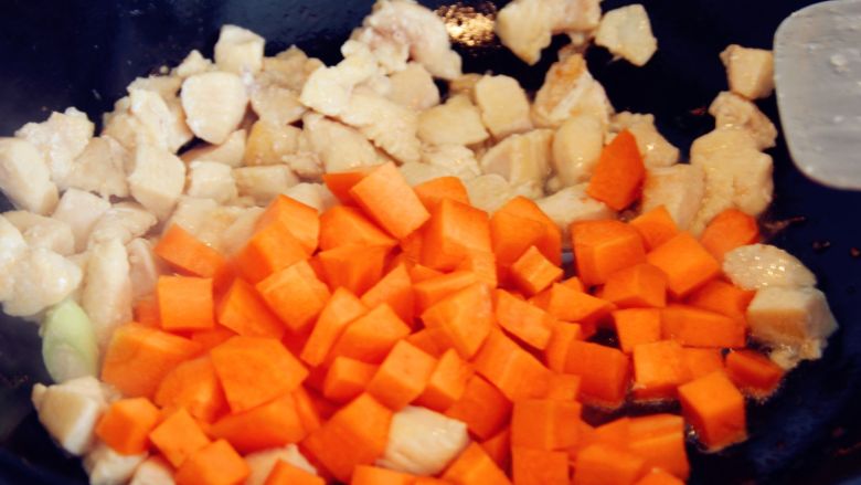 五彩鸡丁焖饭,炒至鸡丁变色之后放入胡萝卜丁。