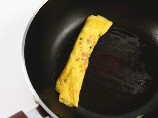 番茄金蛋烧,待鸡蛋液凝固后，用铲子挑起蛋饼的一边，卷成鸡蛋卷，挪至一边。