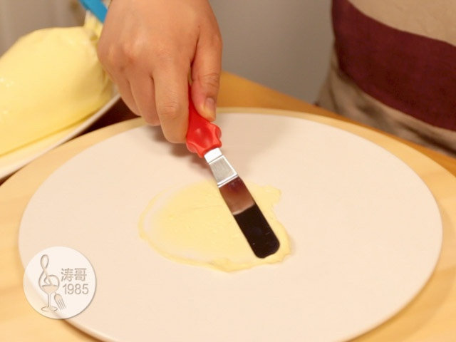黄桃裙边蛋糕,用蛋糕小抹刀抹平，这是为了固定蛋糕，平面圆盘放置在一个蛋糕转盘上，方便后续的操作