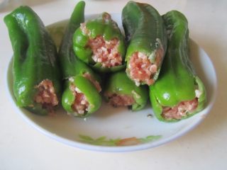 青椒酿肉,用筷子将调制好的肉馅塞入青椒中；