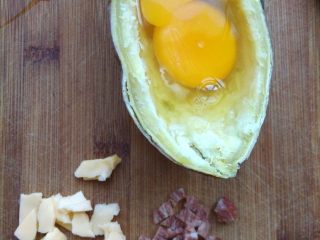 红薯奶酪焗蛋,将一个鸡蛋打进坑里，用牙签扎破蛋黄表面的膜，让蛋黄流出来。同时将培根和少许切达奶酪切小丁。