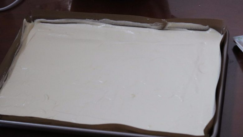 马斯卡彭芝士草莓卷,7.把蛋糕糊倒入铺有油布的烤盘内 振动气泡 表面可以用刮板刮平
